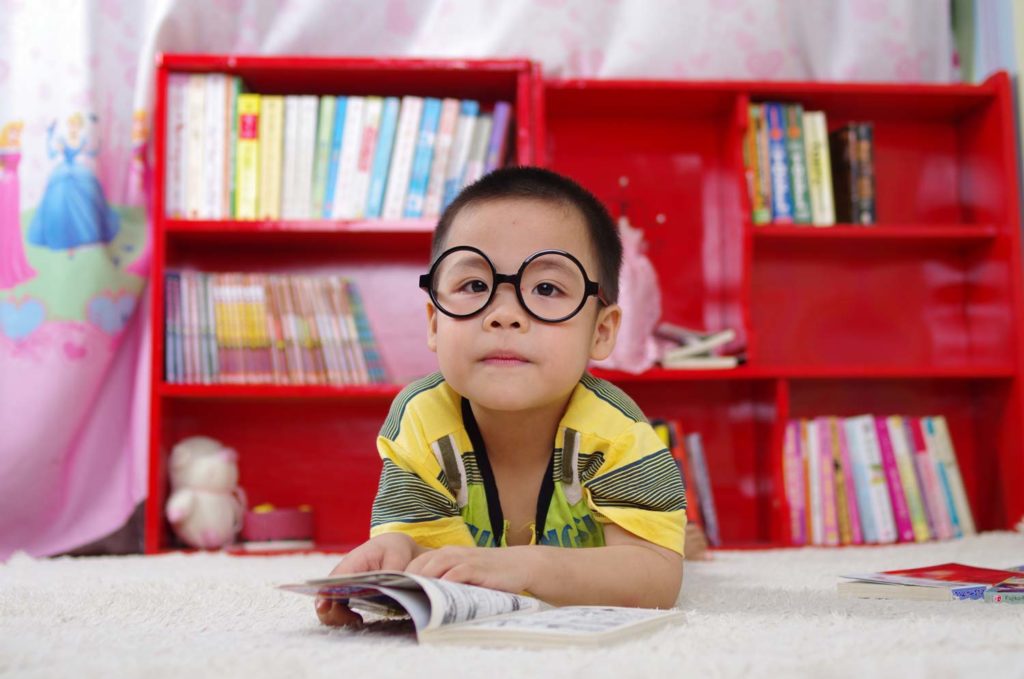 Child laying on floor reading book