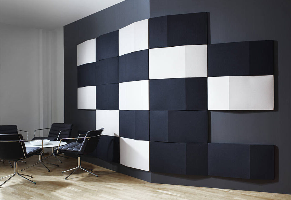 black and white acoustic panels on wall with table and swivel chairs on wooden floor