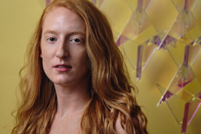 woman with red hair and white shirt in front of a yellow background