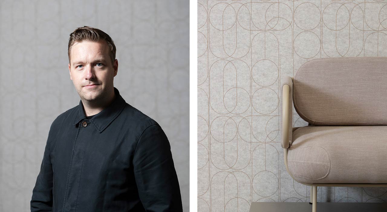 tan acoustic panel with print behind chair and designer on right